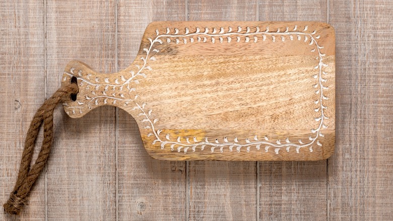 A hand carved cutting board with a rope lanyard.