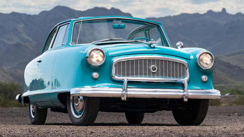 Turquoise 1953 Nash Rambler parked on dirt with mountains in the background