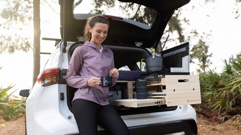 A Roadloft kit user stirring a cup of coffee by their SUV