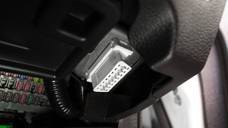Close-up view of an OBD port under a car dashboard