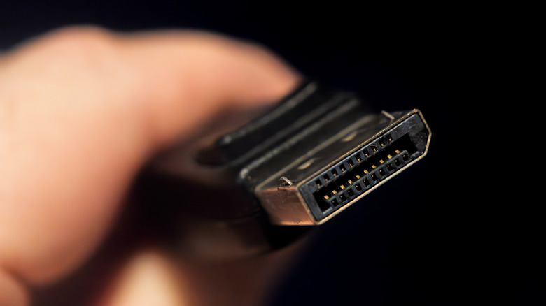 Person's hand holding a DisplayPort cable, with a close-up on its connector