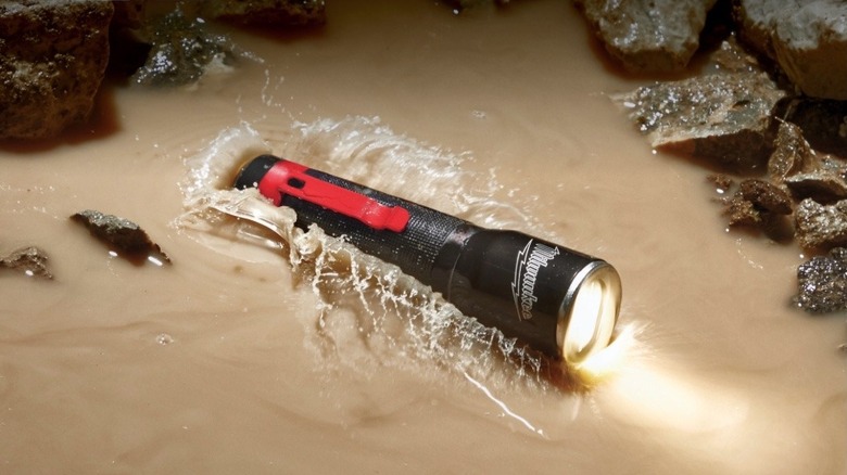 Milwaukee flashlight splashing into a puddle