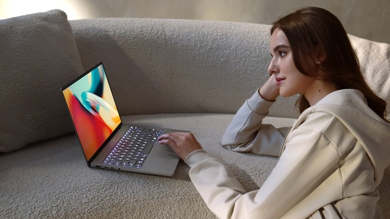 Person using ASUS Zenbook A14 laptop on couch