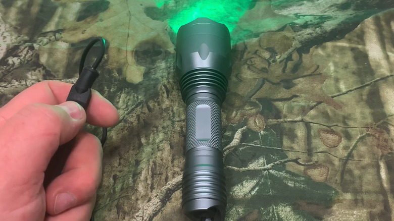 A person testing out a green light flashlight on some camo fabric