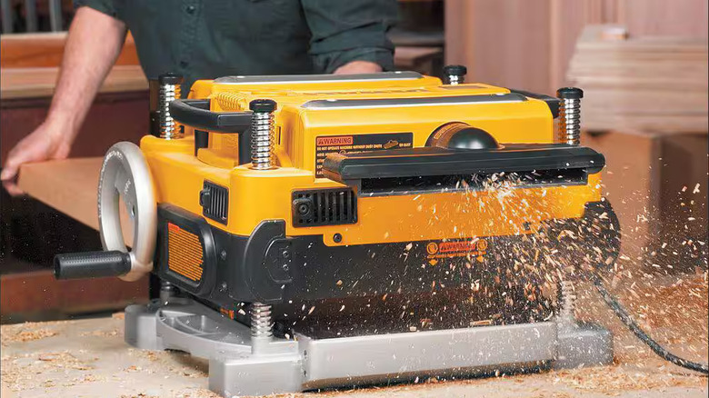 A person feeds a length of wood into a DeWalt powered planer