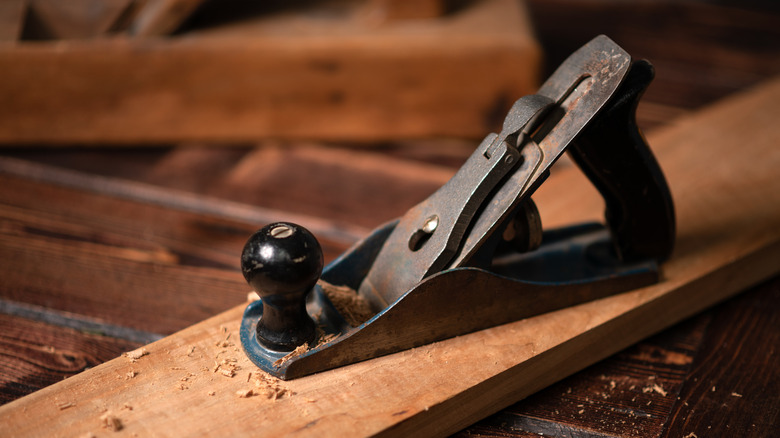 A hand planer on top of a long wooden board
