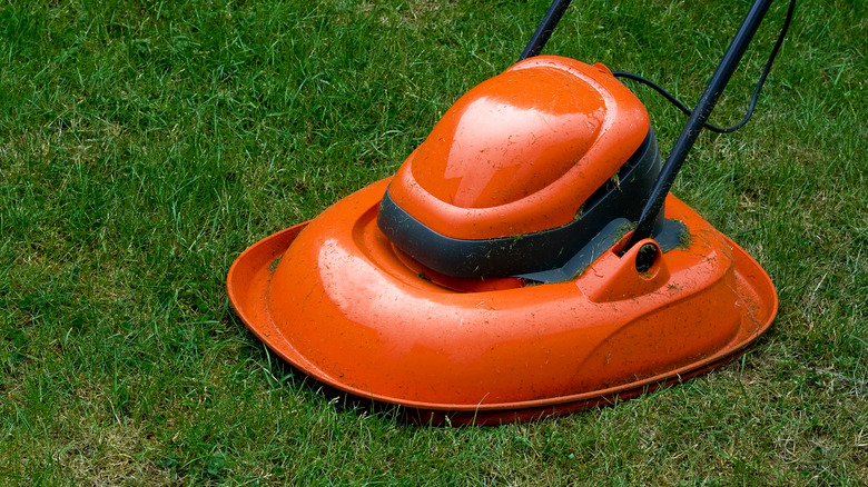 A close-up of an orange hover lawn mower on some grass