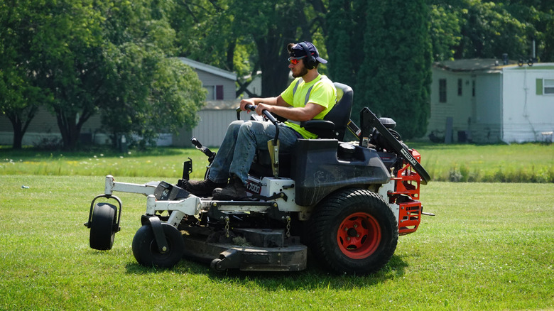 A professional mowing the lawn on a zero turn lawn mower