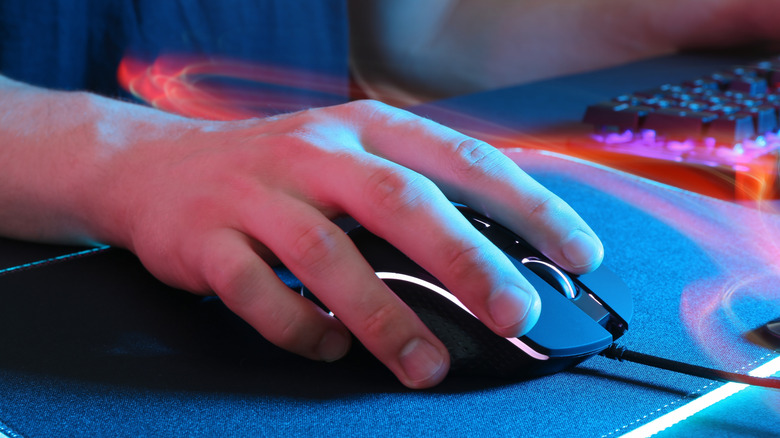 A hand moving a wired mouse on a mousepad