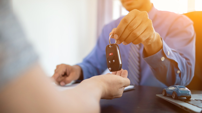 Car dealer giving car keys to owner