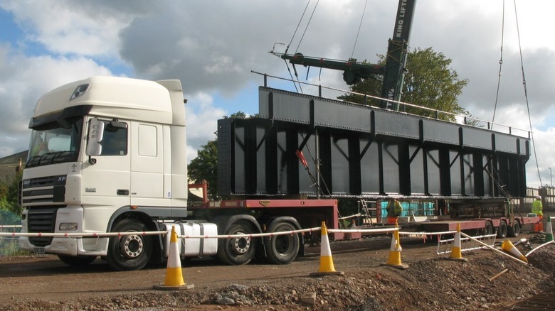 Truck hauling steel side girders off a bridge construction site