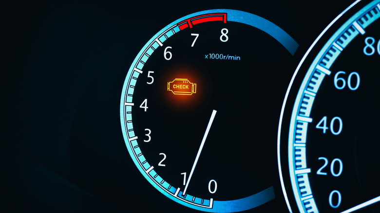 A check engine light is illuminated on a car instrument panel