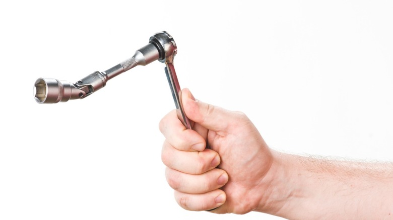 a person holding a ratchet with an extension and a universal joint socket attached