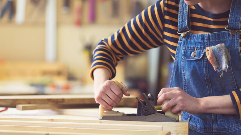Someone using a woodworking jointer in a woodshop