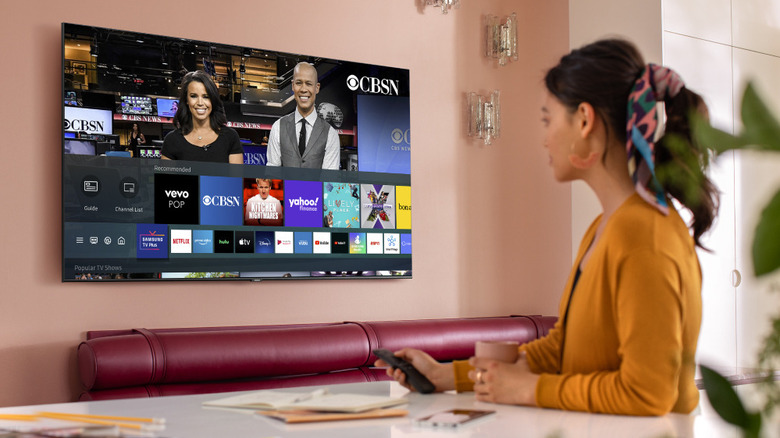 A woman holding remote watching TV