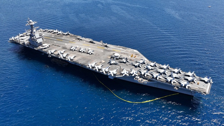 A U.S. Navy aircraft carrier with jets on its deck at open sea