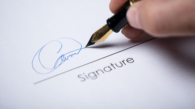 A person signing a document with a fountain pen.