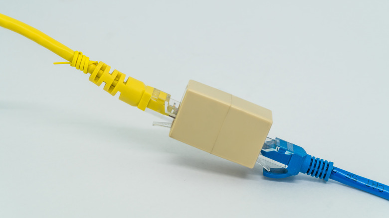 an RJ45 ethernet coupler beng used to connect yellow and blue ethernet cables