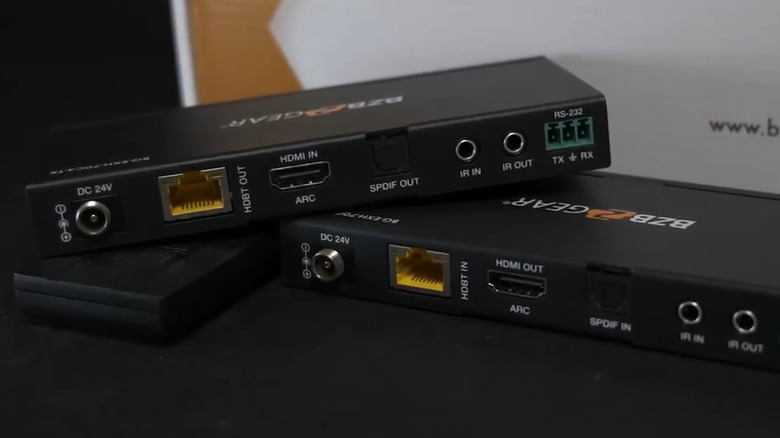 Transmitter and receiver of an HDMI balun placed in front of the packaging box on a black surface