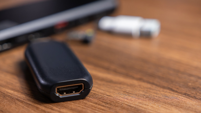 An HDMI adapter on a desk with an out of focus laptop in the background