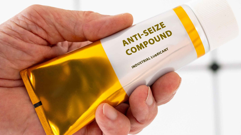 A person holding a tube of generic no-brand anti-seize compound paste