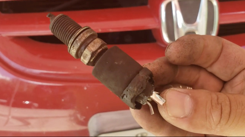 A seized spark plug in front of a Honda Accord