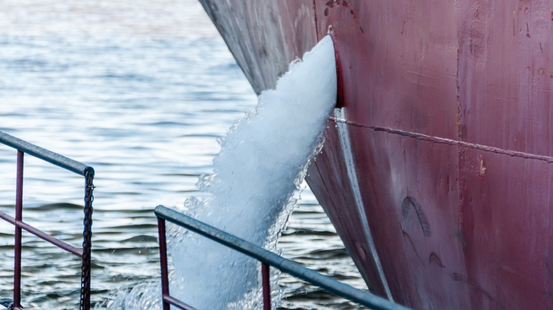 Ballast water shooting out from the side of an anchored ship