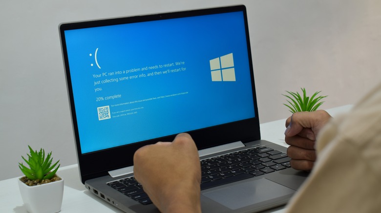 A frustrated person with clenched fists looking at a computer