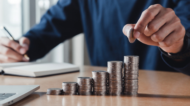 Man stacking up coins signifying saving money.