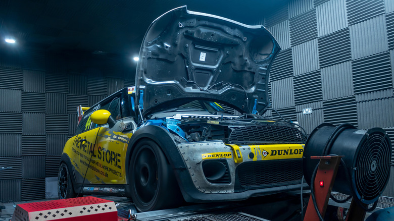 A highly modified Mini Cooper on a dyno with its hood up, front 3/4 view