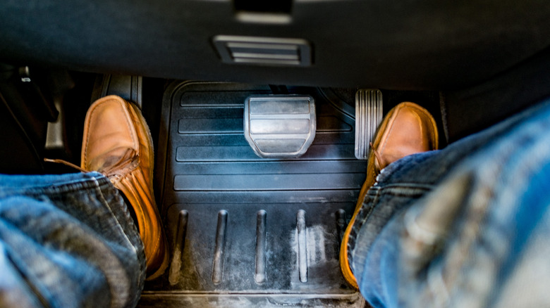 Person with brown shoes stepping on the throttle and dead pedal