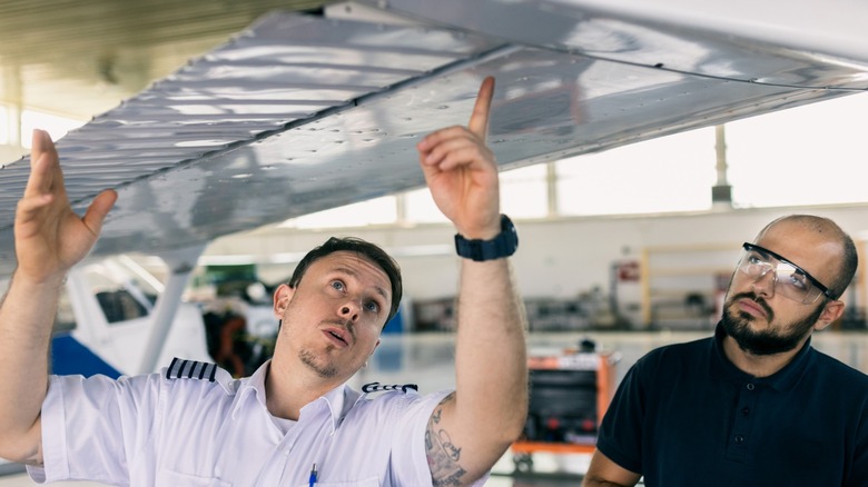 aircraft mechanic and the pilot inspect the plane before take-off