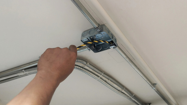 Fish tape being used to thread wire through an electric conduit bend