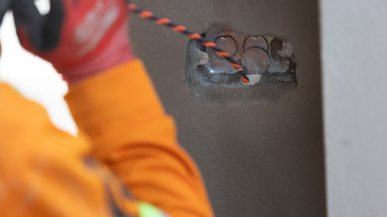 Electrician pulling a fish tape tape through space left for electrical fitting