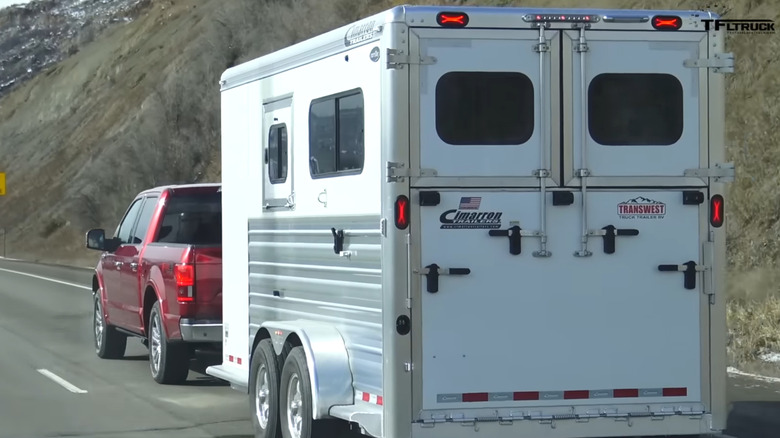 Rear view of a red Ford F-150 truck towing a trailer on the highway