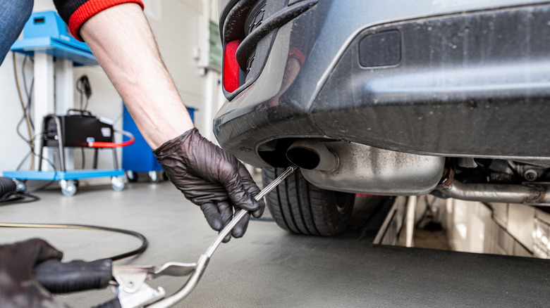 Technician using instrument to measure emissions from a vehicle