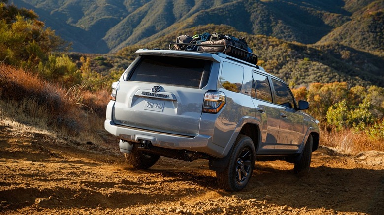 Rear end shot of a 2021 Toyota 4Runner going down a steep off-road trail with mountains in the background.