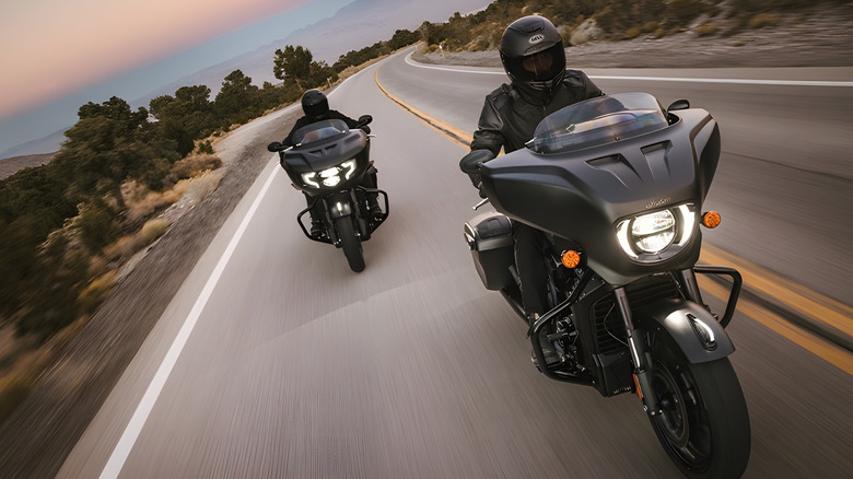 Two riders on Indian motorcycles riding on backroad