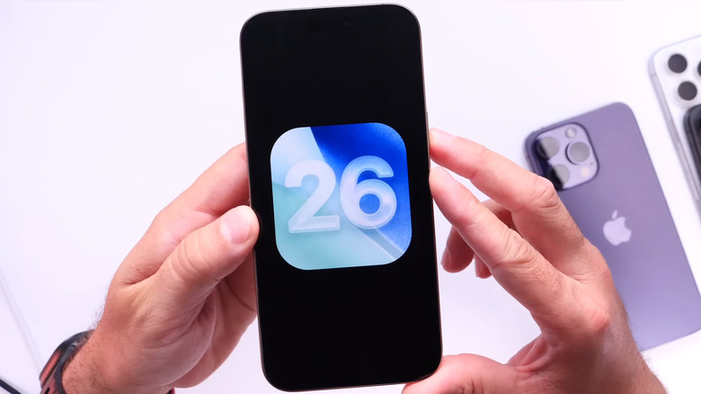 iPhone in hands showing iOS 26 icon