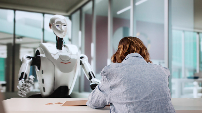 Woman sitting in front of robot