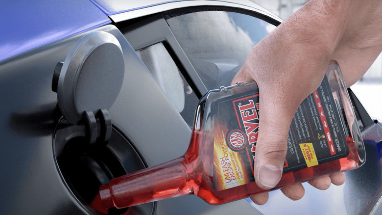 Driver pouring additive into fuel system