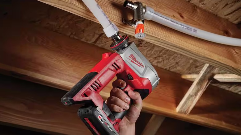 Person using Milwaukee M18 ProPEX expansion tool on PEX pipe