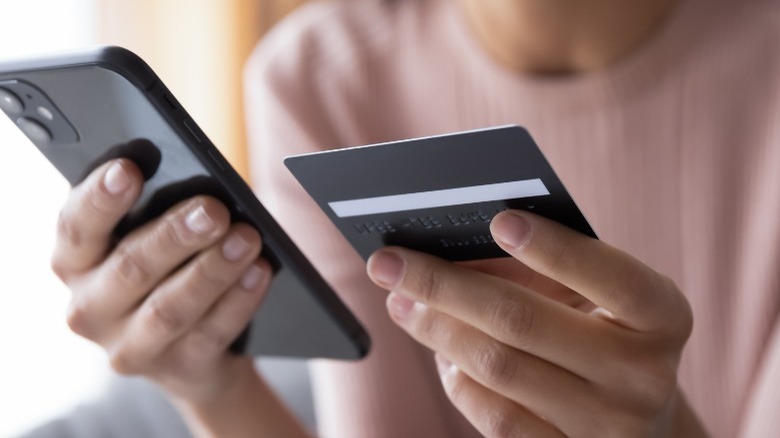 Person holds credit card and iPhone