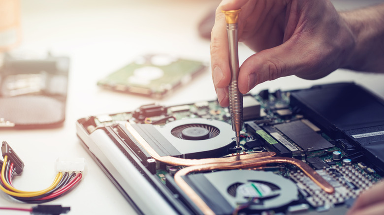 Person repairing laptop with tool