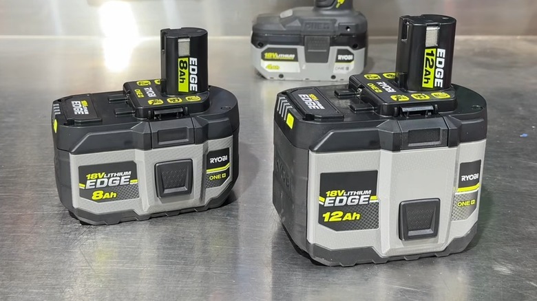 Two Ryobi 18V Edge batteries on a metal surface with a third in the background.