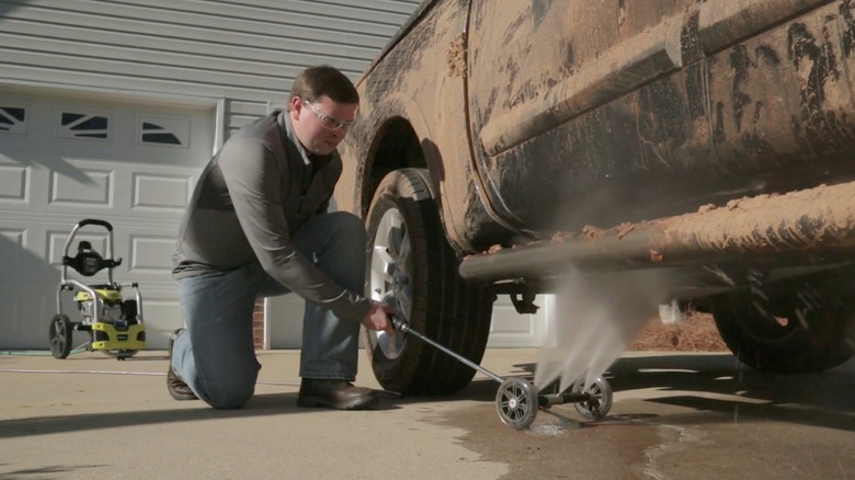 man washing underside of car