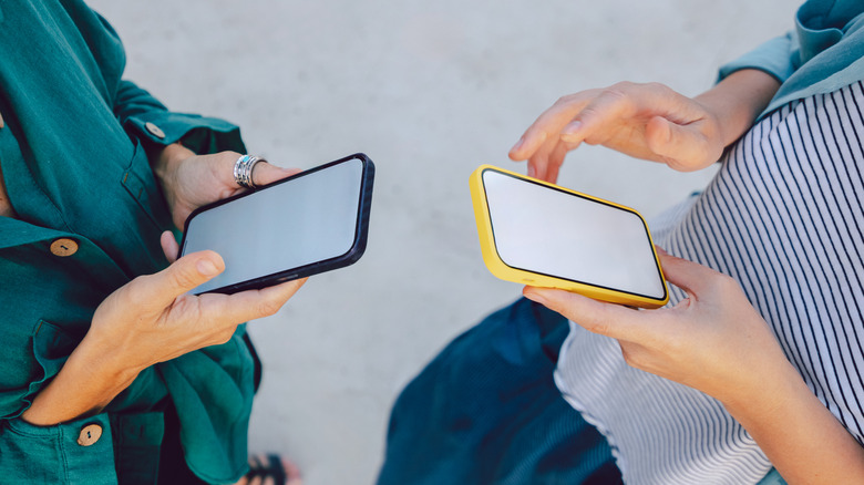 Two people using smart phones.