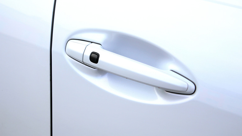 An image of a white car's door handle with keyless entry button.