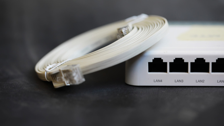 white router with Ethernet cable resting on it placed against a black background