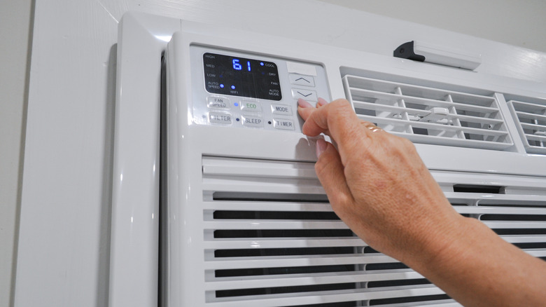 close-up of a person changing temperature on an air conditioner unit